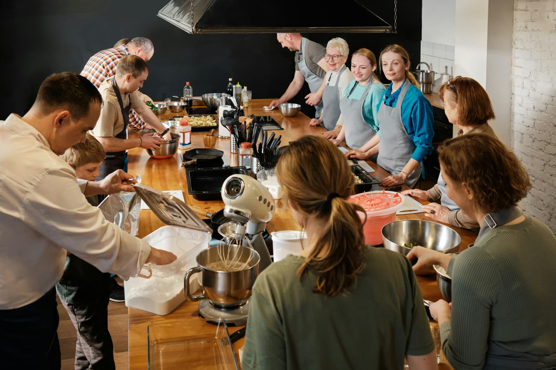 A group cooking class gathered around a wooden kitchen island