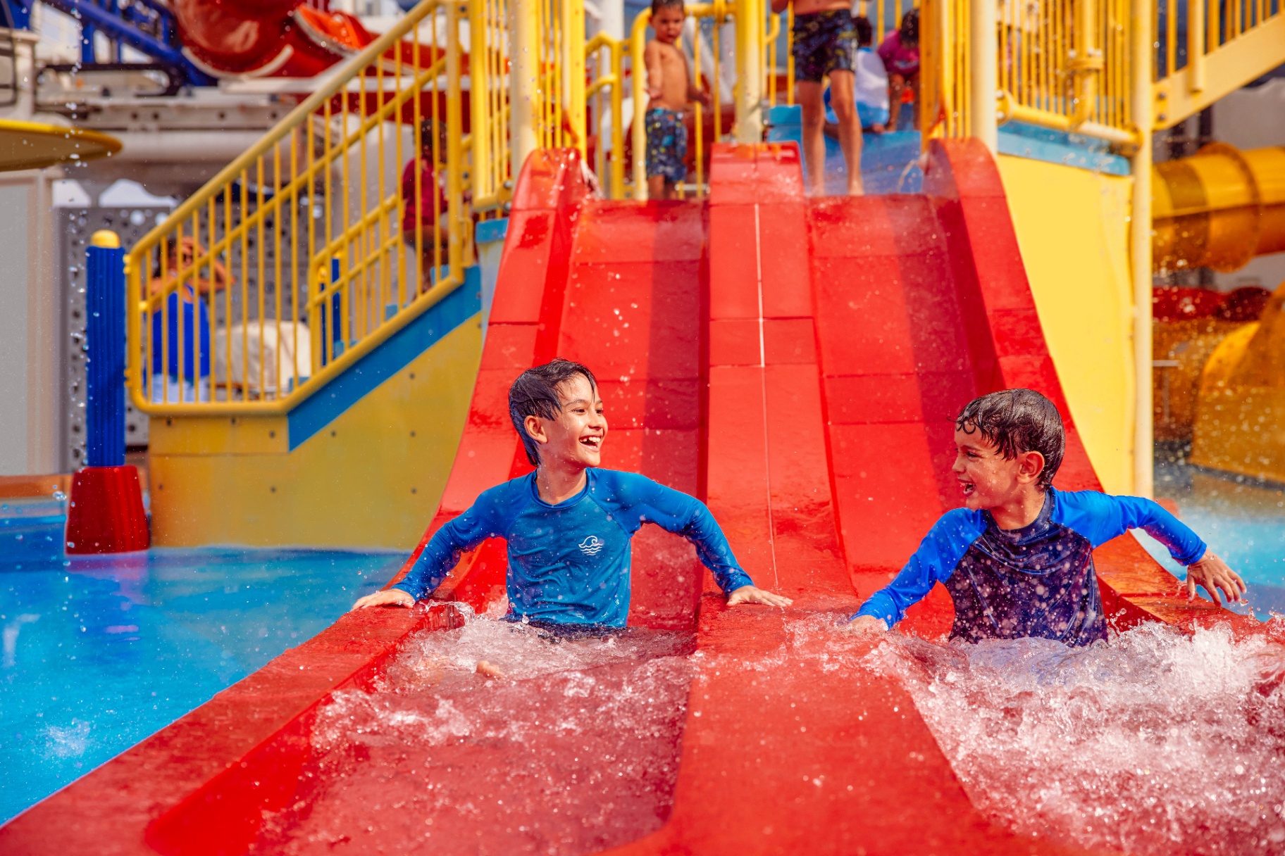 Two boys laughing as they splash down the racing slides at Carnival's WaterWorks park