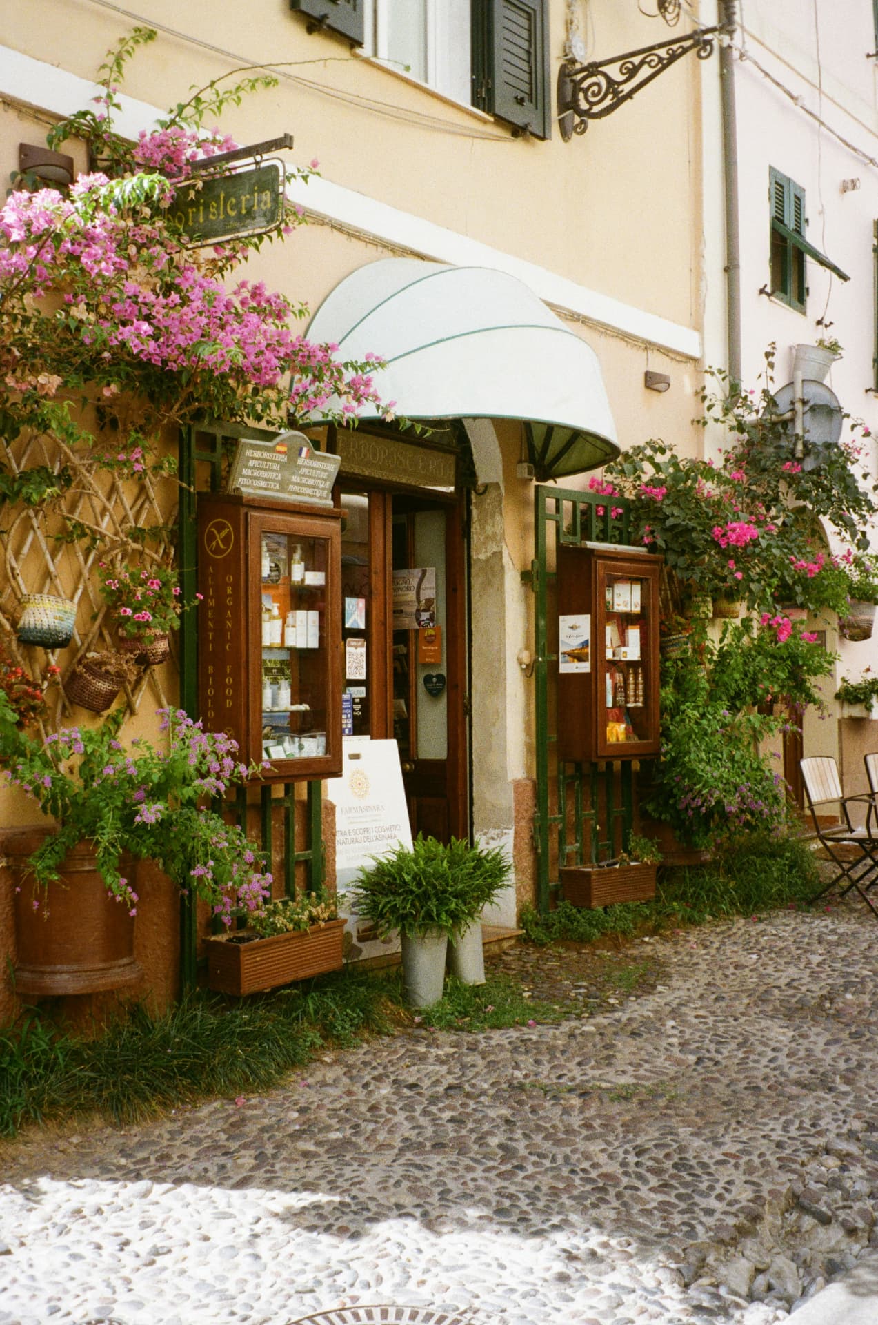 A flower-covered shopfront on a cobblestone street