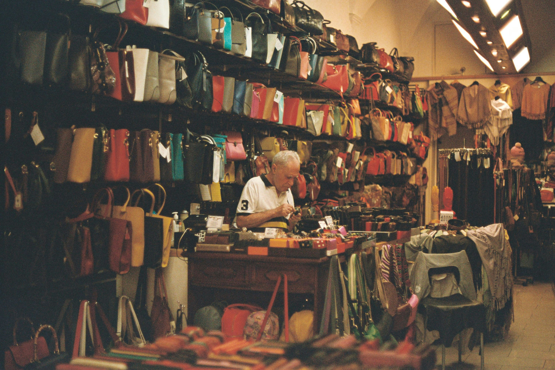 A leather goods artisan working behind the counter of his boutique