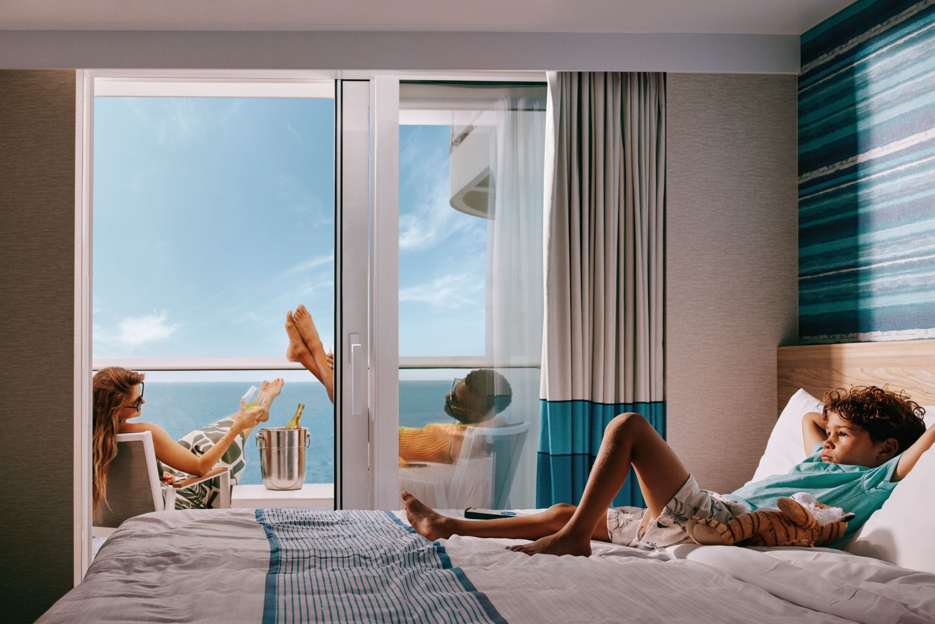 A couple relaxing on a Carnival balcony cabin with ocean views and a bottle of champagne on ice