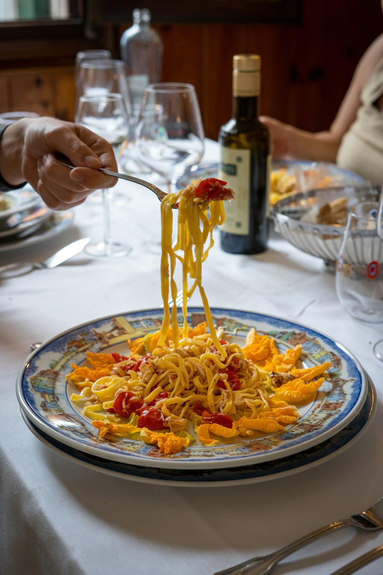 A plate of fresh ribbon pasta with tomatoes and squash blossoms